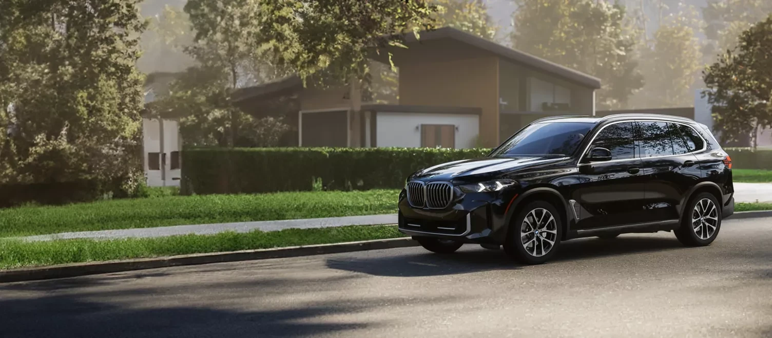 A black BMW X5 parked on a leafy residential street